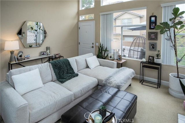living area featuring light colored carpet and baseboards