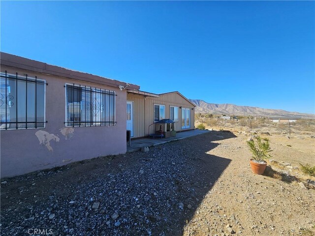 31940 Zircon Rd, Lucerne Valley, CA 92356 - view of side of home with a mountain view, stucco siding, and a patio area