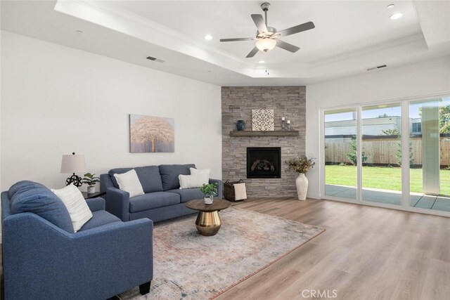 living room featuring ceiling fan, a tray ceiling, wood finished floors, and visible vents