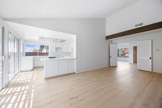 unfurnished living room featuring high vaulted ceiling, visible vents, and a wealth of natural light