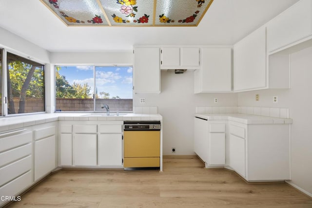 kitchen with tile counters, a healthy amount of sunlight, and dishwasher