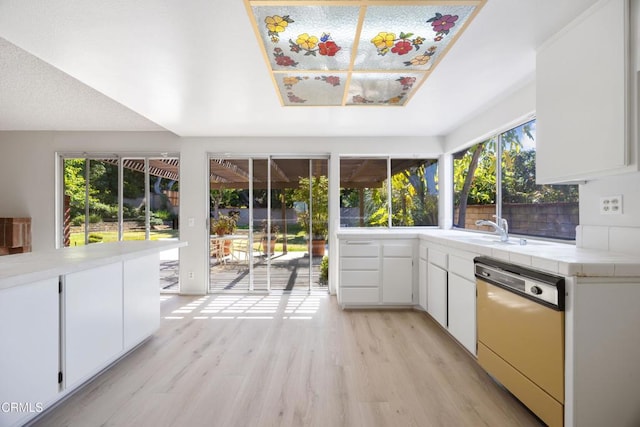 interior space featuring a sink, tile countertops, dishwashing machine, and a wealth of natural light