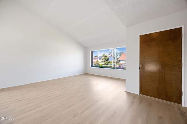 empty room with light wood-style floors and vaulted ceiling