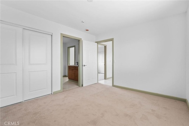 12185 Atsina Rd, Phelan, CA 92371 - unfurnished bedroom featuring a closet, connected bathroom, baseboards, and light carpet