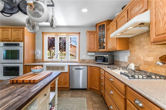 33660 White Feather Rd, Acton, CA 93510 - kitchen with stainless steel appliances, under cabinet range hood, a sink, butcher block counters, and glass insert cabinets