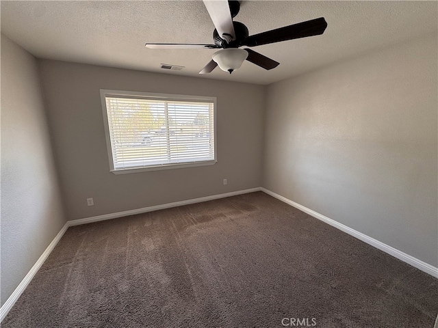 empty room with a textured ceiling, ceiling fan, visible vents, and dark colored carpet