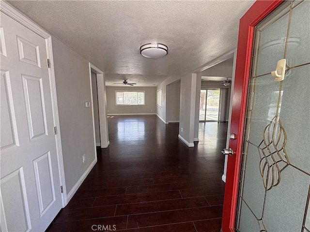 hallway featuring baseboards, a textured ceiling, and wood finished floors