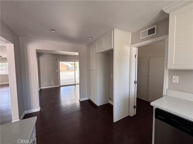 kitchen with plenty of natural light, stainless steel dishwasher, white cabinets, and visible vents