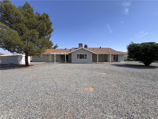 ranch-style house featuring a chimney and stucco siding