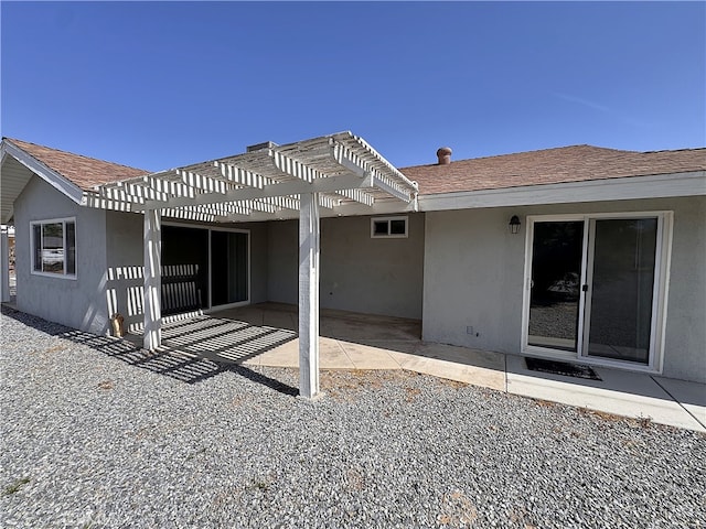 back of house with roof with shingles, a pergola, stucco siding, and a patio area