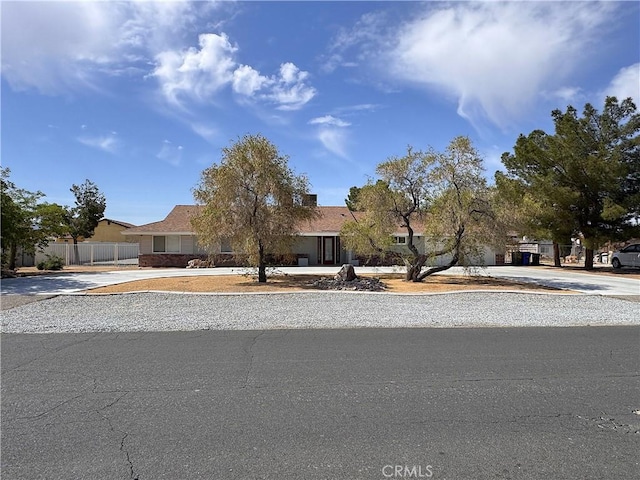 view of property hidden behind natural elements with fence and driveway