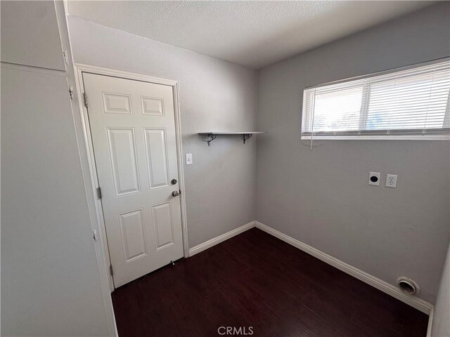 clothes washing area featuring laundry area, baseboards, a textured ceiling, electric dryer hookup, and dark wood finished floors