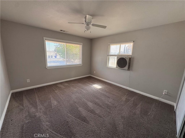 empty room featuring a ceiling fan, baseboards, visible vents, and dark carpet