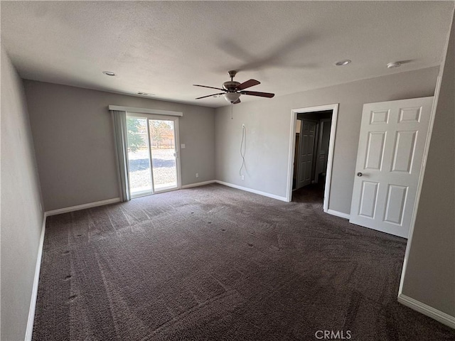 unfurnished room with a ceiling fan, baseboards, and dark carpet