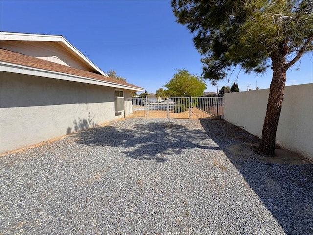 view of yard featuring a gate, fence, and gravel driveway