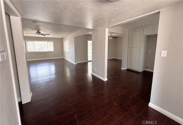 spare room featuring baseboards, a textured ceiling, ceiling fan, and dark wood finished floors
