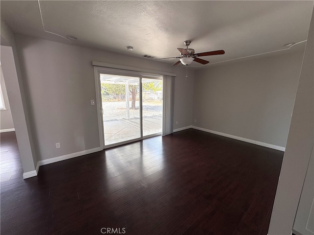 empty room featuring baseboards, dark wood-type flooring, ceiling fan, and visible vents