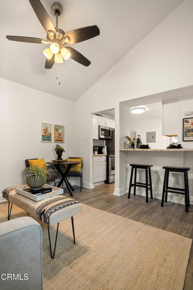 living area with baseboards, ceiling fan, dark wood-style flooring, and high vaulted ceiling