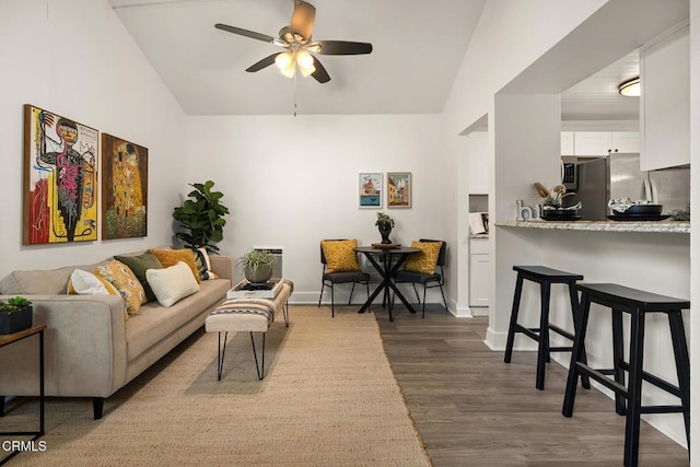 living area with baseboards, a ceiling fan, vaulted ceiling, and dark wood-style floors