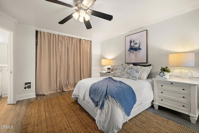 bedroom featuring crown molding, dark wood-style flooring, a ceiling fan, and heating unit