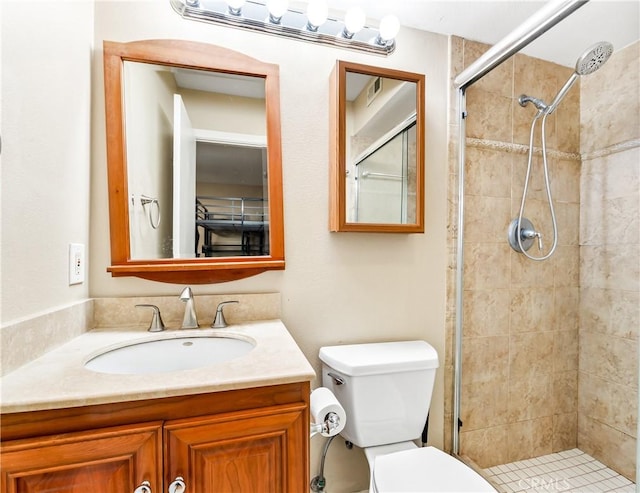 bathroom featuring toilet, tiled shower, and vanity