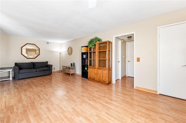 living room with baseboards, visible vents, and light wood-type flooring