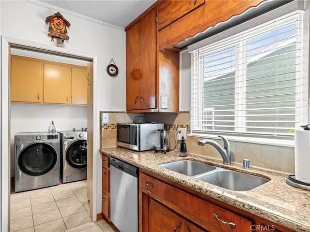 kitchen with ornamental molding, washer and dryer, a sink, appliances with stainless steel finishes, and light tile patterned floors
