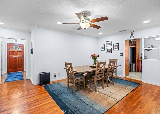 dining area with visible vents, crown molding, light wood finished floors, and ceiling fan