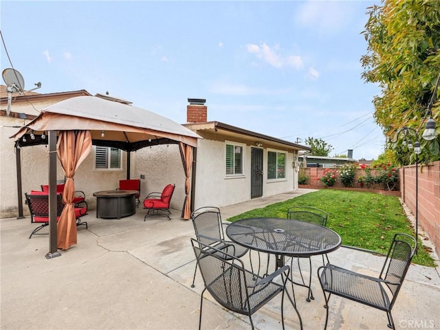 view of patio / terrace with a gazebo, a fire pit, a fenced backyard, and outdoor dining space