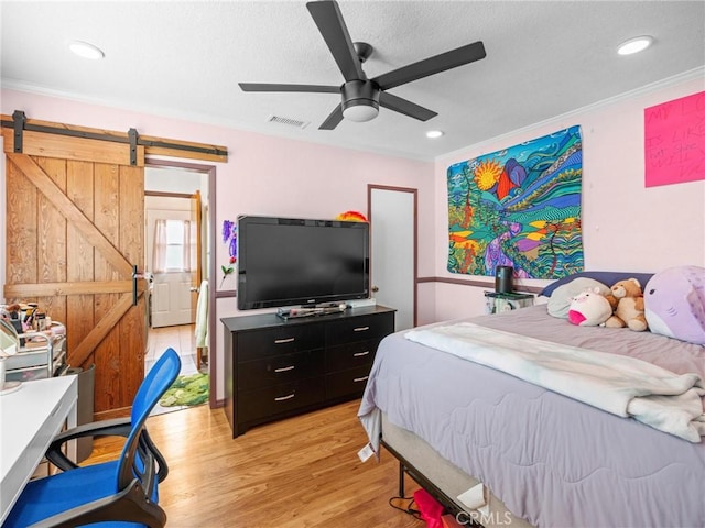bedroom featuring visible vents, crown molding, a barn door, light wood finished floors, and recessed lighting