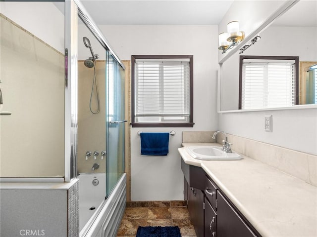 bathroom featuring shower / bath combination with glass door, baseboards, and vanity