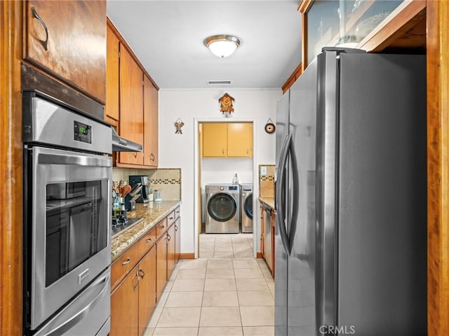 kitchen featuring independent washer and dryer, visible vents, appliances with stainless steel finishes, light tile patterned floors, and under cabinet range hood