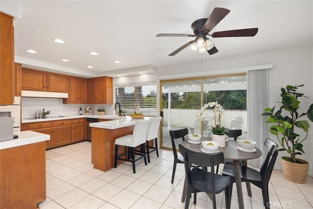 kitchen featuring a ceiling fan, brown cabinets, dishwasher, light countertops, and black electric stovetop