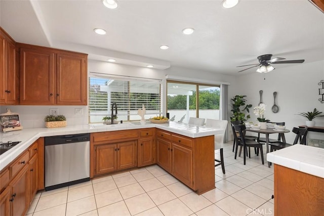 kitchen with a sink, a peninsula, dishwasher, and brown cabinets