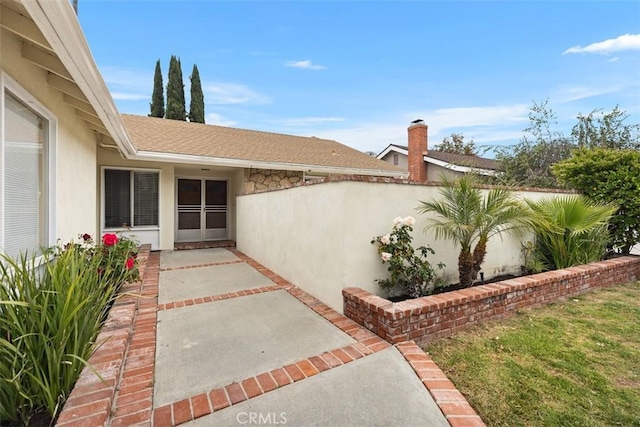 exterior space featuring fence, a patio, stucco siding, and roof with shingles