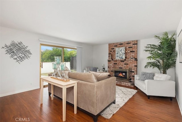 living room with baseboards, dark wood finished floors, and a brick fireplace