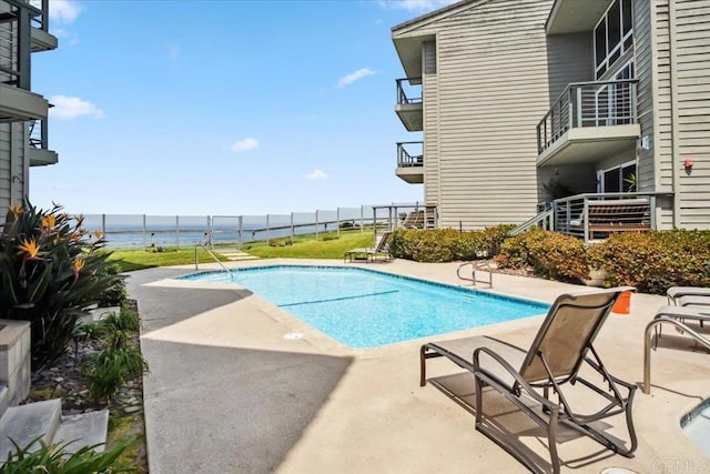 view of pool with a fenced in pool, a patio, and a water view