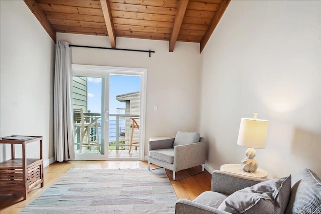 living area featuring baseboards, lofted ceiling with beams, light wood finished floors, and wooden ceiling
