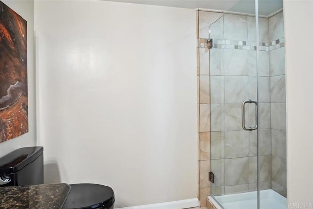 bathroom featuring toilet, baseboards, and a stall shower