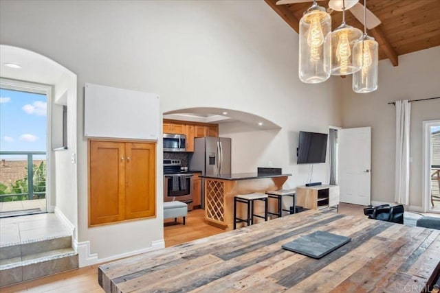 dining area with arched walkways, light wood-type flooring, high vaulted ceiling, and a chandelier
