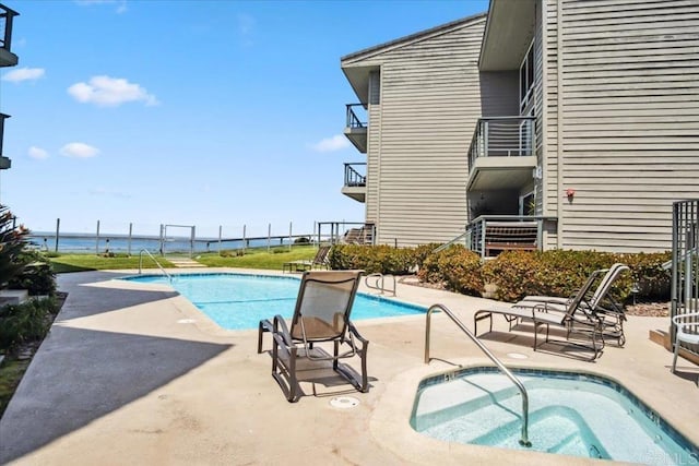 pool with a water view, a community hot tub, and a patio area