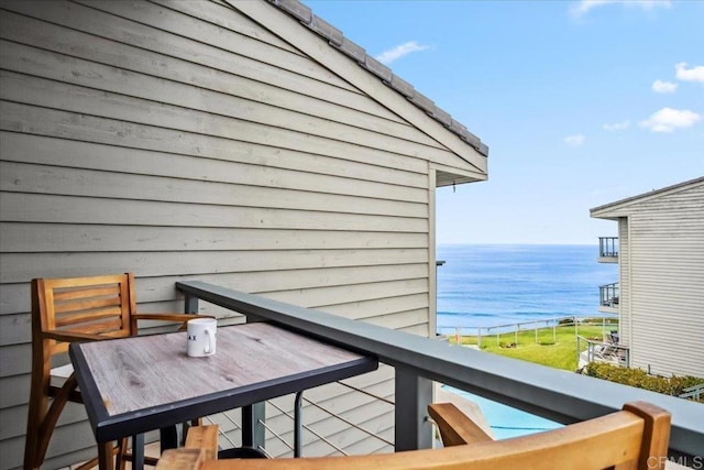 balcony with outdoor dining area and a water view