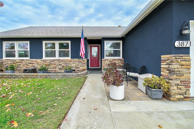 3871 San Mateo Ave, Riverside, CA 92504 - view of exterior entry with a lawn, roof with shingles, stucco siding, and stone siding