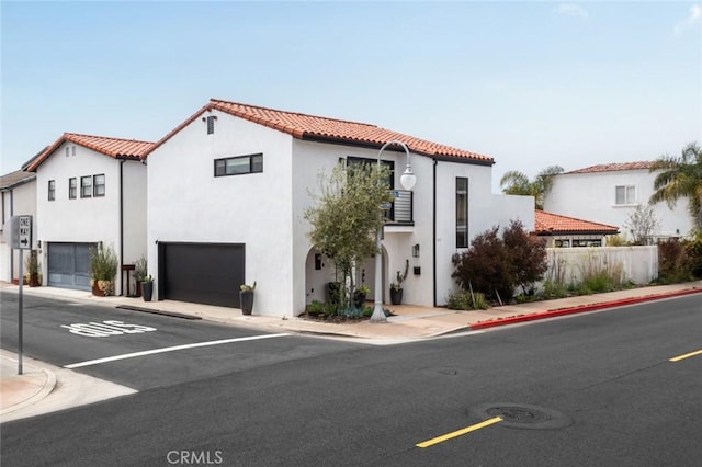 mediterranean / spanish home featuring stucco siding, a tiled roof, fence, and a garage