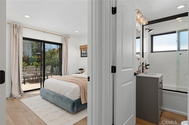 bedroom featuring recessed lighting, access to exterior, a sink, and light wood finished floors