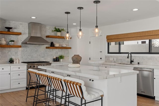 kitchen featuring open shelves, wall chimney range hood, tasteful backsplash, a sink, and stainless steel appliances