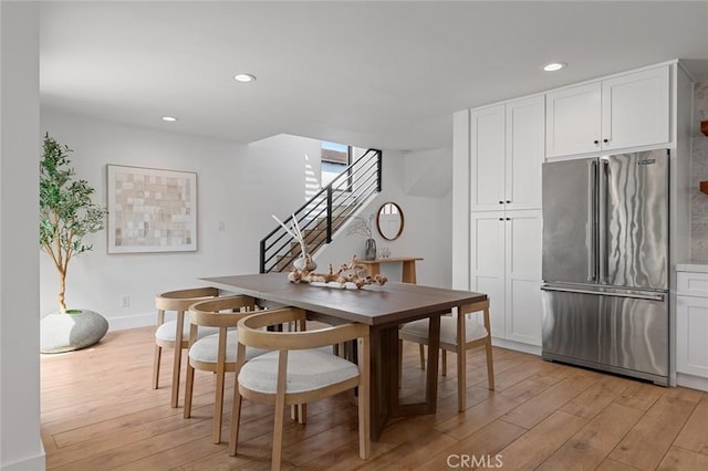 dining area with light wood-type flooring, recessed lighting, stairs, and baseboards