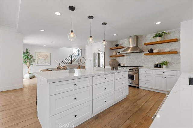 kitchen featuring open shelves, appliances with stainless steel finishes, wall chimney exhaust hood, white cabinetry, and tasteful backsplash