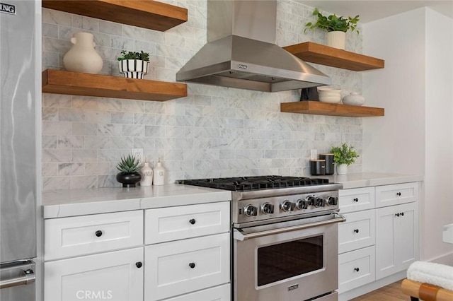 kitchen featuring wall chimney range hood, appliances with stainless steel finishes, decorative backsplash, and open shelves