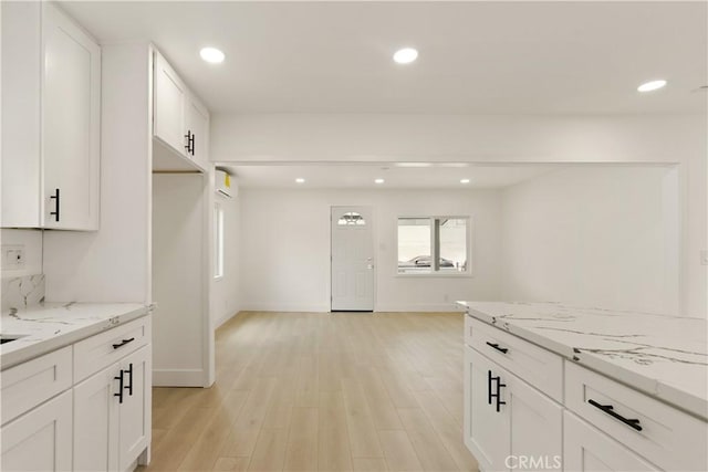 kitchen with light stone counters, light wood-style flooring, recessed lighting, baseboards, and white cabinetry